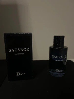 Dior Sauvage Eau de Parfum - Dior Sauvage Eau de Parfum är en ikonisk herrdoft i en elegant mörkblå glasflaska med svart kork. Flaskan har en stilren och modern design med tydlig logotyp och text i vitt. Perfekt för dig som gillar fräscha och maskulina parfymer.