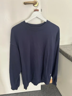 Mörkblå sweatshirt från Vaillent - En stilren mörkblå sweatshirt från Vaillent i storlek M. Tröjan har rund halsringning, långa ärmar och ribbade muddar vid ärmslut och nederkant. Perfekt för en avslappnad och clean look. Materialet känns mjukt och bekvämt mot huden.