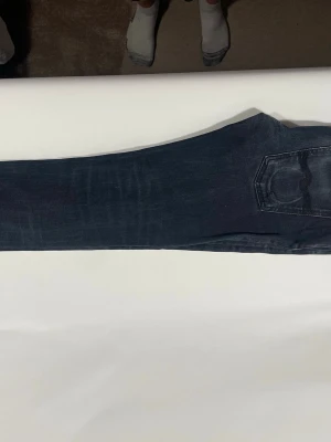 Svarta slim jeans från Nudie - Säljer ett par svarta jeans med slime ben och klassiska bakfickor. Jeansen har en tvättad look med subtila slitningar och kontrastsömmar. Passar perfekt till en avslappnad stil och har bälteshällor i midjan.
