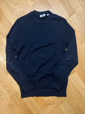 Svart rundhalsad tröja WE fashion - Säljer denna stilrena svarta långärmadetröja från WE i storlek S (men kan även passa M) med rund halsringning och långa ärmar. Tröjan har ribbade muddar vid ärmslut och nederkant, vilket ger en snygg passform. Perfekt att matcha med jeans eller kjol för en clean look. Vid frågor, extra bilder eller liknande är det bara att kontakta mig!