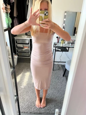 Ljusbeige ärmlös långklänning - Säljer en stilren och enkel långklänning i ljusbeige ton. Klänningen är ärmlös med smala axelband och har en kroppsnära passform som framhäver figuren. Perfekt för dig som gillar minimalistisk och modern stil.