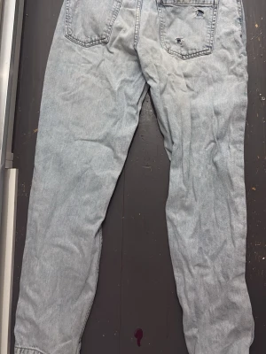 Ljusblå mom jeans från FB Sister - Säljer ett par ljusblå mom jeans från FB Sister i storlek M. Jeansen har hög midja, raka ben och slitningar på bakfickan för en trendig look. Klassisk femficksmodell i mjuk denim med snygg tvätt.