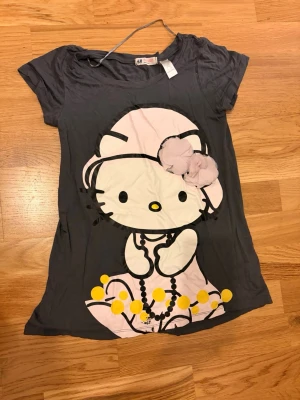 Hello Kitty T-shirt - Säljer en söt Hello Kitty T-shirt köpt från H&M. Den är 164 vilket motsvarar XS och kanske till och med S! Finns defekt som är fotad.