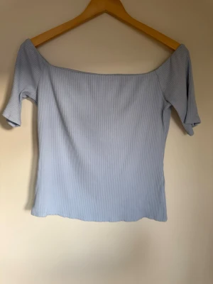 Ljusblå ribbad offshoulder topp - Säljer en ljusblå ribbad topp med offshoulder-design och korta armar.