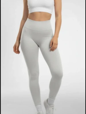 Ljusgrå  leggings - Säljer ett par ljusgrå leggings med hög midja och sömlös design. De är tighta och stretchiga, perfekta för träning eller chill. Materialet ser ut att vara mjukt och följsamt, vilket ger en snygg siluett och skön känsla. Passar dig som gillar stilrena och enkla plagg.