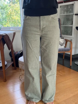 Gröna jeans  - Säljer ett par ljusgröna jeans med rak passform och medel hög midja. Jeansen har klassiska fem fickor och stängs med dragkedja och knapp. Materialet är denim i bomull och de har en avslappnad, trendig look.
