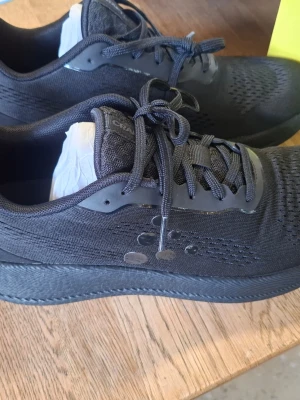 Svarta sneakers med meshdetaljer - Snygga helsvarta sneakers med ventilerande mesh på ovandelen och klassisk snörning. Skorna har diskreta detaljer på sidan och en bekväm, dämpad sula som passar perfekt till streetwear eller träning. Materialet är en mix av textil och syntet.