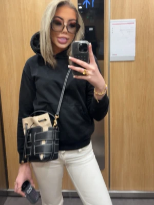 Svart och beige bucket bag - Säljer en trendig bucket bag i svart och beige med justerbar axelrem. Väskan har ett coolt rutmönster i svart läder och beige tyginsida med dragsko. Perfekt för dig som vill ha en unik och snygg accessoar till din outfit.