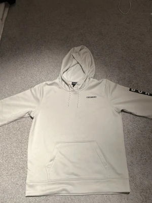 Ljusgrå hoodie från Burton - Snygg ljusgrå hoodie från Burton med klassisk känguruficka och justerbar huva med dragsko. Diskret Burton-logga på bröstet och tryck på ena ärmen. Tillverkad i mjukt bomullsmaterial som är perfekt för chill dagar. Säljer 400 kan möjligtvis gå med på priser ner till 250