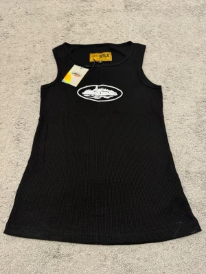 Corteiz 4Starz Alcatraz Tank Top – Svart - Snygg svart ribbad linnetopp med ett vitt tryck framtill. Toppen har ärmlös design och rund halsringning. Perfekt för en avslappnad och trendig stil. Materialet känns mjukt och följsamt mot kroppen. Helt nytt!!