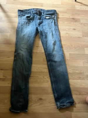 Replay jeans - Säljer ett par blå slim fit jeans med snygga slitningar och tvättade detaljer. Klassisk femficksmodell med dragkedja och knapp i midjan. Jeansen har raka ben och kontrastsömmar. Perfekta för en avslappnad och trendig look.