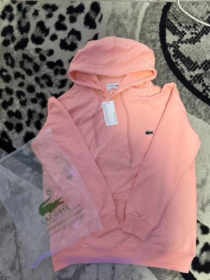 Lacoste hoodie  - En rosa snygg Lacoste hoodie, hoodien är aldrig använd och helt ny. Pris kan diskuteras vid snabb affär.