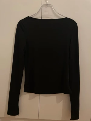 Svart långärmad topp från BikBok - En enkel och stilren svart långärmad topp från BikBok. Modellen har en rak passform och är tillverkad i ett mjukt och stretchigt material som sitter snyggt på kroppen. Perfekt basplagg att matcha med allt i garderoben.