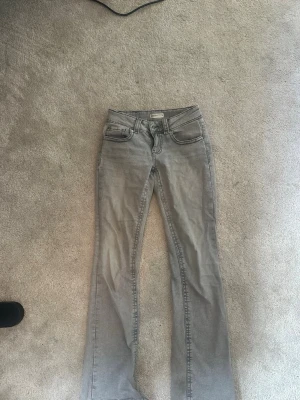 Grå bootcut jeans från Gina tricot - Säljer ett par grå bootcut jeans från West Jeans i storlek 34. Jeansen har klassisk femficksdesign, bälteshällor och en snygg tvättad look. Perfekta för dig som gillar en avslappnad men ändå trendig stil.