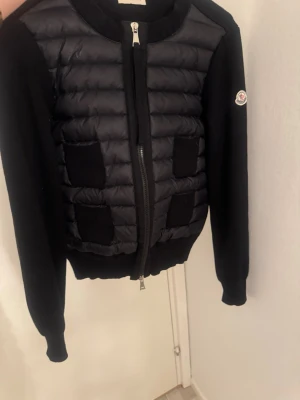 Svart cardiganjacka med quiltad front - Snygg svart cardiganjacka med qr kod, nfc logga på armen och qr scann. Den har även moncler taggar och en dustbag❤️