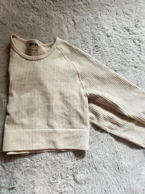 Beige ribbad långärmad träningströja Aim’n - Beige croppad topp i ribbad med lång ärm och rund hals. Enkel och stilren design som passar perfekt till både träning och chill. Materialet är mjukt och stretchigt för skön passform.