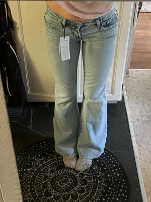 Ljusblå bootcut jeans med slitning - Säljer ett par ljusblå fulllengt flare lowwaist Jeans från Gina tricot aldrig andvända. Stl S