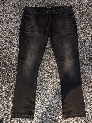 Svarta flared jeans - Säljer ett par svarta flared jeans med slitningar och diskreta detaljer framtill. Dom är använda men ser helt nya ut. Priset får alltid att diskutera