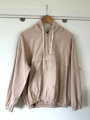Miss Sumey - beige rosa jacka / hoodie - storlek M - Härlig tunn rosa beige jacka / anorak med huva från Miss Sumey i storlek M. Stilren modell med halv dragkedja och praktisk ficka framtill. Långa ärmar och resår i ärmslut och nederkant. Finvävt material i 100% bomull, så bra material som andas. Mycket gott skick, som ny!