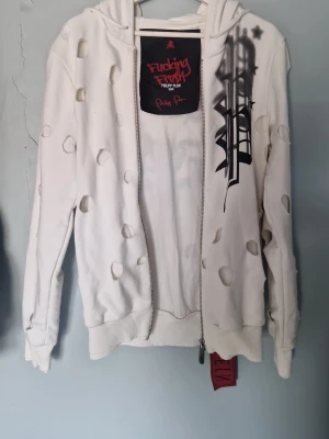 Vit hoodie Philipp Plein med tryck - Säljer en vit hoodie från Philipp Plein med stort svart tryck 'Fucking Fresh' på ryggen och coola slitningar över hela plagget. Hoodien har huva, dragkedja och ribbade muddar. Märkesdetaljer och edgy streetstyle-vibe. Priset kan även diskuteras