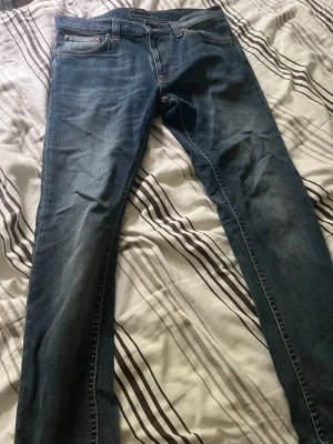 Blå raka jeans från nudie jeans  - Säljer ett par klassiska blå jeans från nudie jeans med rak passform och fem fickor. Jeansen har en snygg tvättad look och är tillverkade i slitstarkt denimtyg. Perfekta för dig som gillar tidlös stil och vill ha ett par jeans som funkar till det mesta. Storleken är W30, L 32. Hör av er om det finns några frågor 