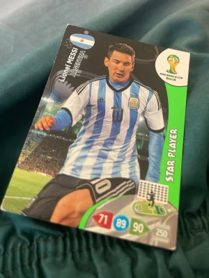 Fotbollssamlarbild Messi VM Brasilien - Cool samlarbild med Lionel Messi i Argentinas landslagströja från FIFA World Cup Brasilien. Kortet har färgstarka detaljer, statistik och texten 'Star Player' på framsidan. Perfekt för dig som gillar fotboll och samlarkort.