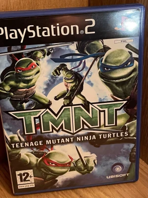 TMNT till PlayStation 2 - Säljer spelet TMNT: Teenage Mutant Ninja Turtles till PlayStation 2. Omslaget är färgglatt med de fyra ninjasköldpaddorna i actionposer. Spelet är ett actionäventyr där du spelar som alla fyra karaktärer och slåss mot fiender i stadsmiljö. Perfekt för dig som gillar klassiska superhjältar.