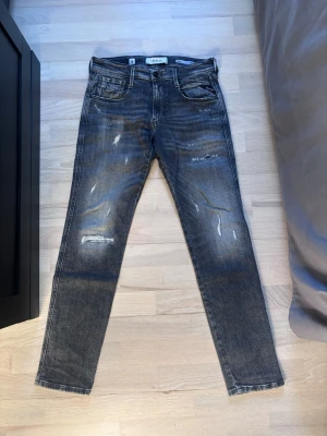 Replay Anbass slim fit - Mörkblå slim fit jeans från Replay ( modell Anbass slim fit)  med slitningar och distressed detaljer på benen. Klassisk femficksmodell med normal midja och dragkedjegylf. Perfekta för en avslappnad och trendig look.