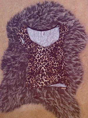 Leopardmönstrad t-shirt med v-ringning - Snygg t-shirt med leopardmönster och v-ringad hals. Kortärmad modell i stretchigt material som sitter tajt och framhäver figuren. Perfekt för dig som vill sticka ut med ett djurmönster i garderoben.