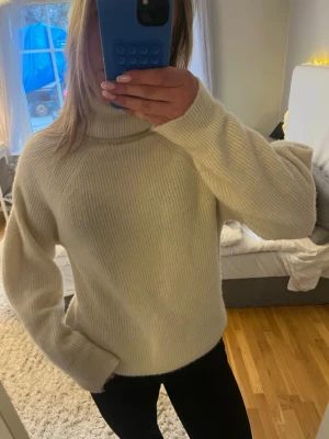 Vit polotröja från Anna Field - Mysig vit stickad polotröja från Anna Field. Tröjan har en hög polokrage, lång ärm och är tillverkad i ett mjukt, ribbstickat material. Perfekt för kalla dagar och enkel att matcha med olika outfits.