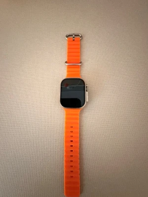 Snygg klocka! - Snygg klocka med fyrkantig urtavla i silverfärgad metall och ett riktigt iögonfallande orange silikonband. Klockan har en stor skärm och robust design, perfekt för dig som gillar teknik och vill sticka ut med din wearable. Fråga direkt om du har några frågor och priset är inte hugget i sten!💯💯