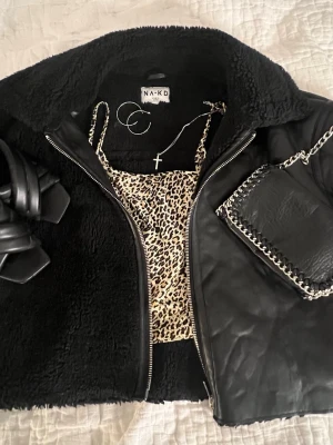 Svart teddyjacka från NA-KD - Snygg svart teddyjacka från NA-KD med mjuk, fluffig insida och krage. Utsidan har detaljer i fejkskinn och dragkedja framtill. 