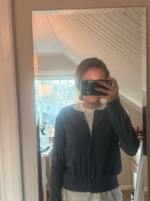 Mörkblå basic kofta med rund hals - En enkel och stilren mörkblå kofta med rund halsringning och knappar framtill. Koftan har långa ärmar och ribbade muddar vid ärmslut och nederkant. Perfekt att slänga över en t-shirt för en avslappnad look. Knappt använd, som ny! 