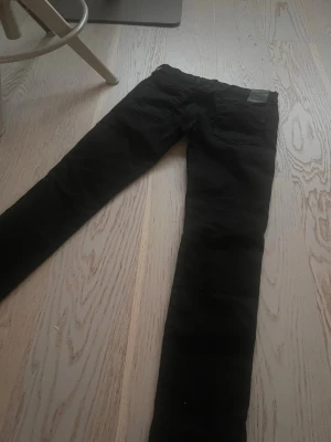 Svarta replay jeans - Säljer ett par svarta replay jeans med klassisk femficksdesign och normal midja. Jeansen har smal passform och är tillverkade i ett stretchigt material för extra komfort. Perfekta till en avslappnad eller trendig look. Personen på bilden är 180cm och storleken på byxorna är S