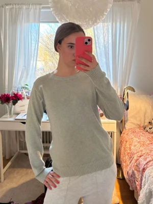 Ljusgrå stickad tröja - En enkel och stilren ljusgrå stickad tröja med rund halsringning och ribbade muddar vid ärmslut och nederkant. Perfekt basplagg som passar till det mesta och är superbekväm att bära. Tröjan har en avslappnad passform och är gjord i mjukt material.