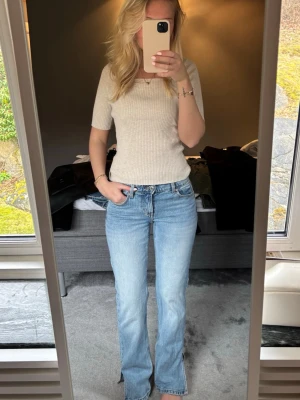 Ljusblå bootcut jeans - Säljer ett par ljusblå bootcut jeans med låg midja. Jeansen har en avslappnad passform över låren och lätt utsvängda ben. 