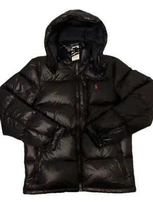 Svart pufferjacka från Polo Ralph Lauren - Säljer en svart pufferjacka från Polo Ralph Lauren med huva och dragkedja framtill. Jackan har en blank finish och den klassiska röda Polo-loggan broderad på bröstet. Perfekt för kalla dagar och riktigt snygg till streetwear-stilen.