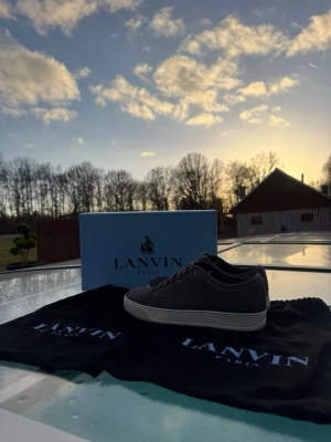 Gråa Lanvin sneakers i mesh och mocka - Snygga gråa sneakers från Lanvin med ovandel i mesh och mocka, vita sulor och klassisk låg profil. Skorna har matchande grå skosnören och diskret design. Perfekta för dig som gillar stilrena och exklusiva sneakers.