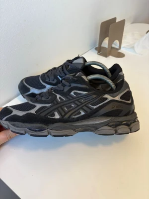 Svarta ASICS Gel-NYC sneakers - Säljer ett par svarta och grå ASICS Gel-NYC sneakers med mesh och mockadetaljer. Skorna har en chunky sula och klassisk snörning. Perfekta för dig som gillar sportig stil och vill ha bekväma sneakers med cool design.