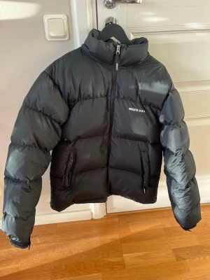 Svart pufferjacka från Axel Arigato - Säljer en svart pufferjacka från Axel Arigato med hög krage och dragkedja framtill. Jackan har två sidofickor med dragkedja och diskret logga på bröstet. Priset är absolut diskuterbart. Nypris 4000