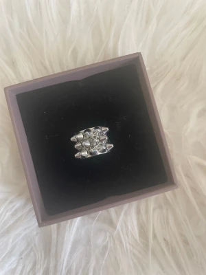 Silvrig peak ring med nitar - Cool silvrig ring med chunky design och flera små nitar på ovansidan. Ringen har en bred form och en modern, edgy look som sticker ut. 💕💕 Nypris 399kr