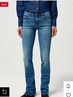 Blå bootcut jeans från Wrangler - Snygga blå bootcut jeans från Wrangler med klassisk femficksdesign och ljus tvätt. Jeansen har normal midja, raka ben med lätt utsvängning och detaljerade bakfickor med signatursöm. Tillverkade i slitstark denim. Säljer då jag inte gillar den typen av jeanstyg som inte är så stretchiga men annars gillade jag dem. Dom är i storleken 30/30 och använda 3 gånger.