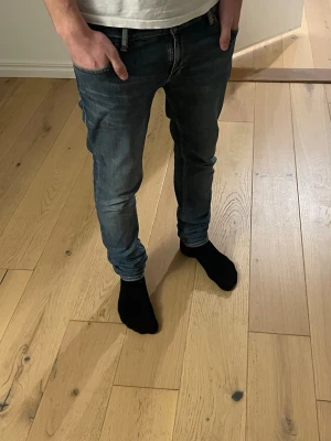 Nudie jeans  - Säljer ett par blå slim fit jeans med klassisk femficksdesign och normalhög midja. Jeansen har en snygg tvättad look och är tillverkade i denim med stretch för extra komfort. Passar perfekt till en avslappnad stil.