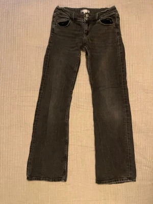 Svarta raka ginatricot jeans med fickdetaljer - Snygga svarta jeans med raka ben och coola fickdetaljer bak med knappar. Klassisk femficksmodell och kontrastsömmar. Perfekta till en avslappnad stil och passar till det mesta. Materialet är denim i bomull.