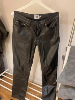Svarta skinnbyxor från 157 - Säljer ett par svarta skinnbyxor från 157 med klassisk femficksmodell och raka ben. Byxorna har bälteshällor och silverfärgade knappar och nitar. Perfekta för dig som vill ha en edgy och trendig look, köptes på vinted!💕