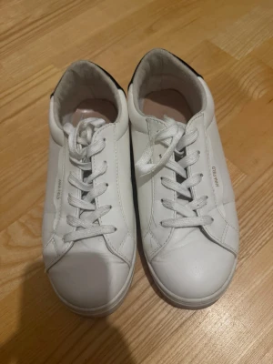 Vita sneakers från Anna Field - Stilrena vita sneakers från Anna Field med klassisk låg design. Skorna har vita snören, diskret logga på sidan och ovandel i slätt syntetmaterial. Perfekta för en clean och enkel look till alla outfits. Storleken är 38,5