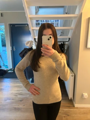 Beige stickad tröja från VILA - Klassisk beige stickad tröja från VILA med rund halsringning och långa ärmar. Tröjan har ribbstickade muddar vid ärmslut och nederkant, perfekt för lager-på-lager och enkel att matcha med olika outfits.