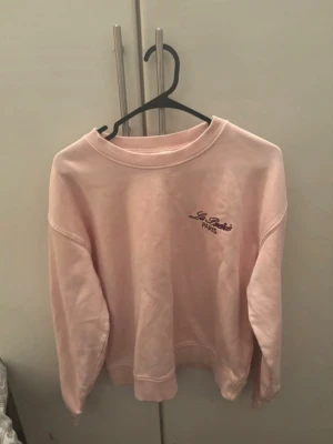 Ljusrosa sweatshirt La Paris Paris - Säljer en ljusrosa sweatshirt från La Paris Paris med broderad logga på bröstet. Tröjan har rund halsringning, långa ärmar och ribbade muddar. Perfekt för en chill och avslappnad stil. För mer bilder/justering av pris skriv gärna❤️🤗