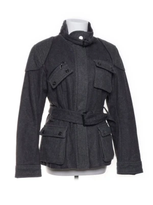 Mörkgrå kappa med bälte - Stilren mörkgrå kappa i ull från purification Garcia med hög krage, fyra stora fickor framtill och bälte i midjan. Kappan har markerade axlar, förstärkta armbågar och knappar på ärmsluten. Säljer då den är för liten för mig. 