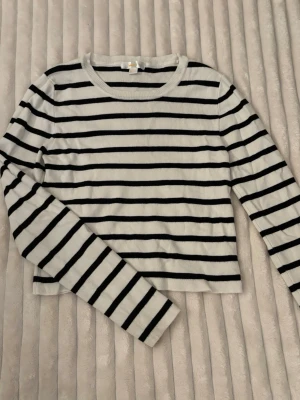 Randig långärmad tröja Gina Tricot - Snygg långärmad tröja från Gina Tricot med svartvita horisontella ränder. Tröjan har rund halsringning och är gjord i mjukt, stretchigt material. Perfekt för en avslappnad och trendig look.